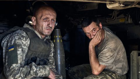 Zwei Soldaten der Ukraine sitzen mit verhärmten Gesichtern in einer Panzerhaubitze