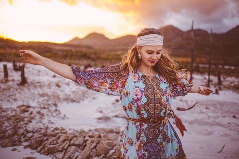 Boho-Stil Mädchen tanzt im geblümten Kleid an einem Sommerabend
