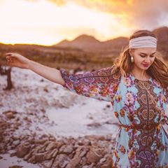 Boho-Stil Mädchen tanzt im geblümten Kleid an einem Sommerabend