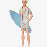 Auch Puppen-Ken hat den Strand gerne. Im rosa-türkis gestreiften Zweiteiler samt Surfbrett versucht er Barbie zu beeindrucken.