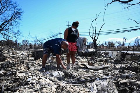 Eine Familie sucht in ihrem niedergebrannten Haus in Lahaina nach Gegenständen.