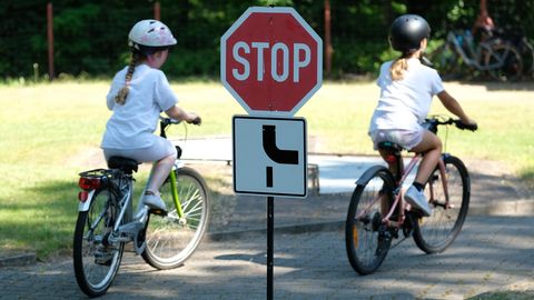 Zwei Kinder auf ihren Fahrrädern, im Vordergrund ein Stopschild