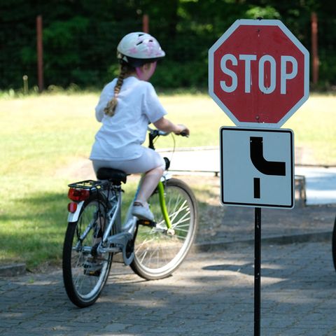 Zwei Kinder auf ihren Fahrrädern, im Vordergrund ein Stopschild