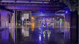 Zwei Feuerwehrleute waten durch das knietiefe Wasser einer Unterführung in Gelsenkirchen, Nordrhein-Westfalen. Heftige Regenfälle haben eine komplette Straße im Stadtteil Schalke überflutet.