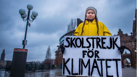 Greta Thunberg in ihrer ikonischen gelben Regenjacke mit ihrem Schild auf dem "Skolstrejk för Klimatet" steht
