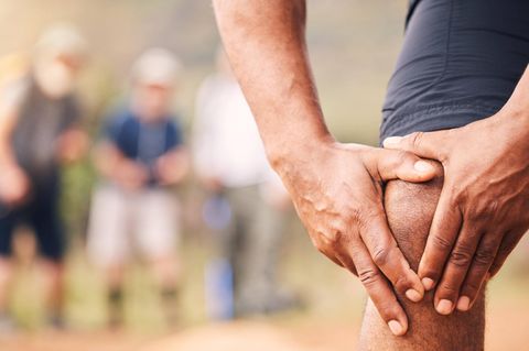 Ein Mann hält sich das Knie vor Schmerzen fest
