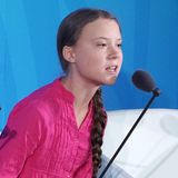 Greta Thunberg in rosa-farbener Bluse am Mikrofon
