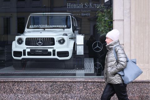 Eine Frau geht vor einem Mercedes-Benz-Autohoaus in Moskau spazieren, im Schaufenster ein weißer Mercedes