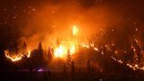 Ein Waldbrand am McDougall Creek erhellt die Nacht an einem Berghang in West Kelowna. Die Größe des Feuers wird klar, wenn man sich das beleuchtete Haus rechts unten im Bild anschaut