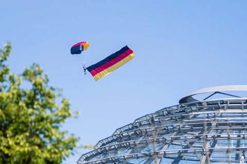 Ein Fallschirmspringer der Bundespolizei fliegt über der Kuppel des Reichstagsgebäudes