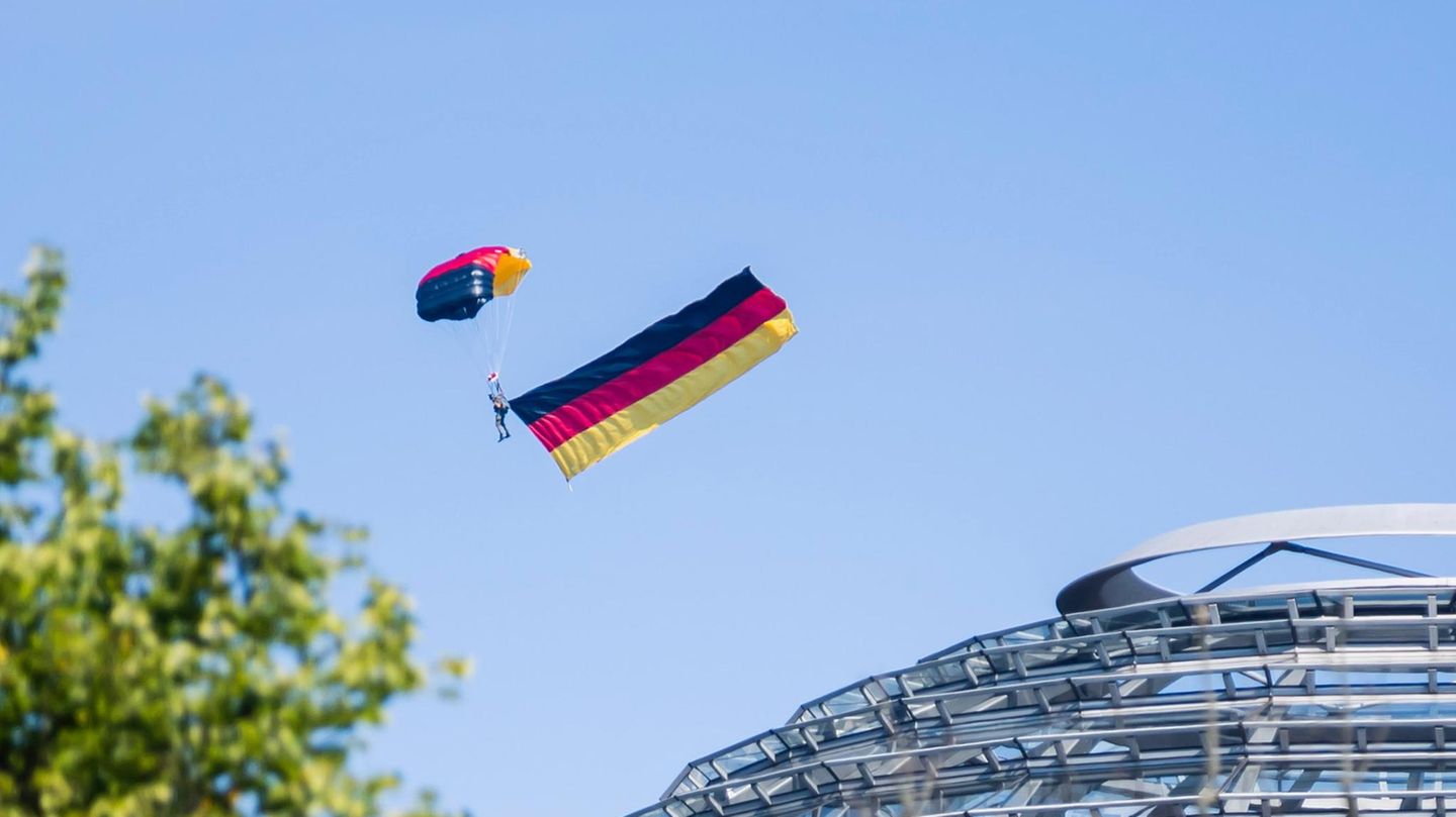 Ein Fallschirmspringer der Bundespolizei fliegt über der Kuppel des Reichstagsgebäudes Ein Fallschirmspringer der Bundespolizei fliegt über der Kuppel des Reichstagsgebäudes