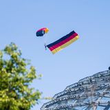 Ein Fallschirmspringer der Bundespolizei fliegt über der Kuppel des Reichstagsgebäudes