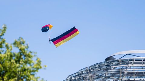 Ein Fallschirmspringer der Bundespolizei fliegt über der Kuppel des Reichstagsgebäudes