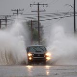 Ein Auto fährt in der Stadt Redlands durch die Fluten.