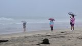 Am Imperial Beach in Kalifornien stehen Frauen im Regen und halten das stürmische Wetter mit ihren Handys fest.