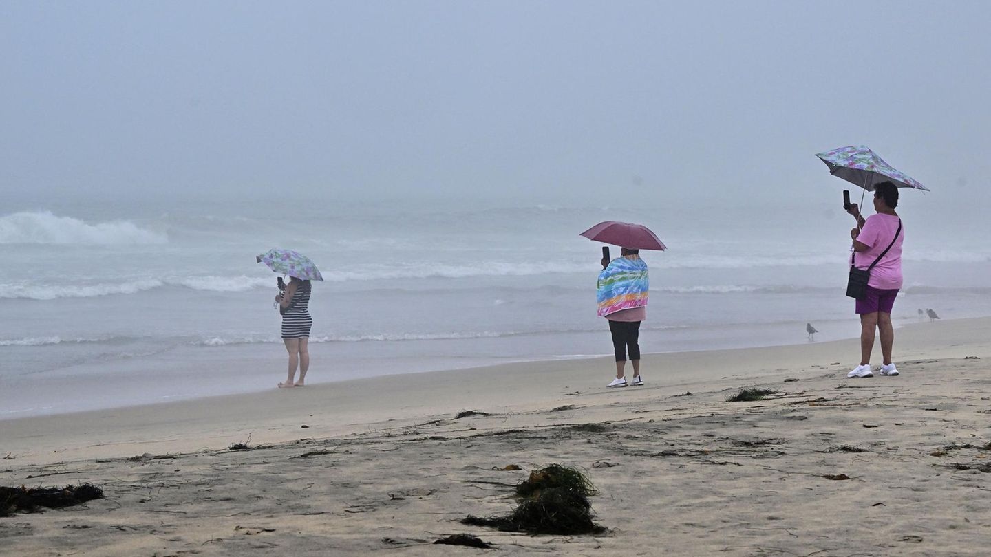 Am Imperial Beach in Kalifornien stehen Frauen im Regen und halten das stürmische Wetter mit ihren Handys fest.