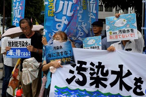 Menschen in Tokio demonstrieren mit Plakaten gegen die Ableitung von radioaktiv verseuchtem Wasser ins Meer