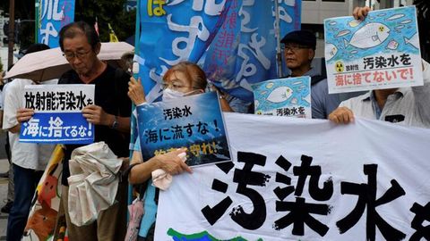 Menschen in Tokio demonstrieren mit Plakaten gegen die Ableitung von radioaktiv verseuchtem Wasser ins Meer