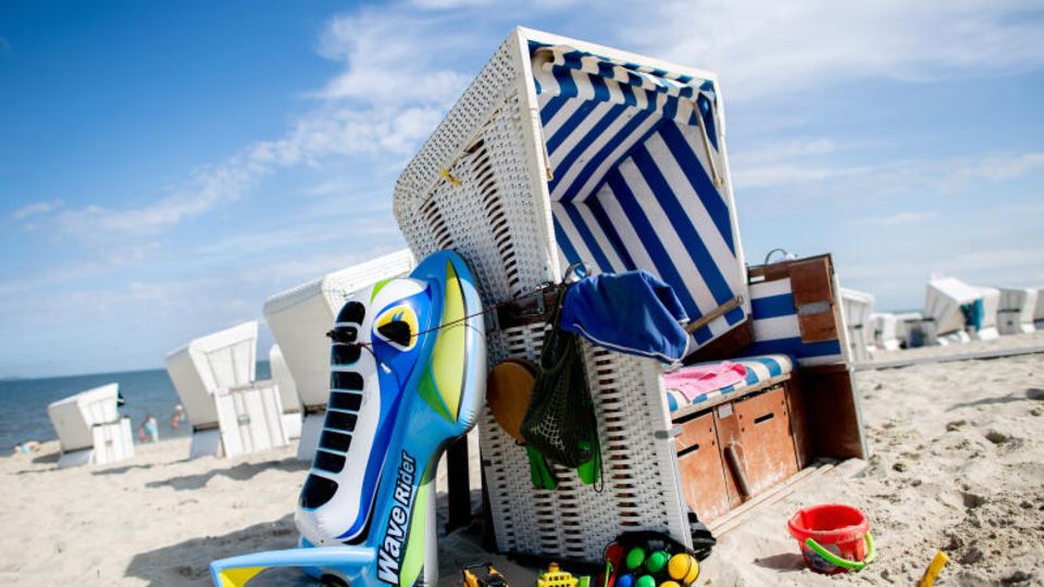 Strandspielzeug liegt bei sonnigem Wetter neben einem Strandkorb am Strand der Insel Wangerooge.