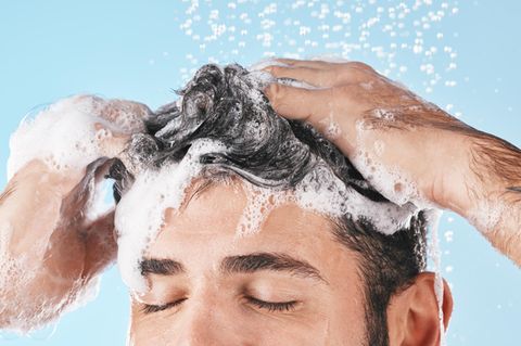 Ein Mann benutzt ein Shampoo gegen fettige Haare
