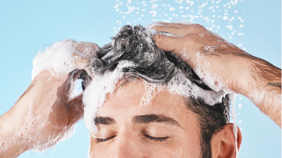 Ein Mann benutzt ein Shampoo gegen fettige Haare