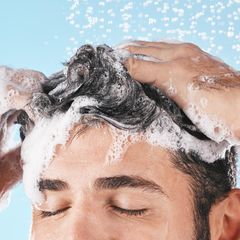 Ein Mann benutzt ein Shampoo gegen fettige Haare