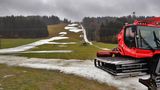  Eine Pistenraupe steht im Januar 2020 auf einer Skipiste, die bei Tauwetter noch teilweise mit Schneeresten bedeckt ist