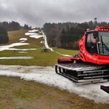  Eine Pistenraupe steht im Januar 2020 auf einer Skipiste, die bei Tauwetter noch teilweise mit Schneeresten bedeckt ist