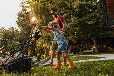 Vater und Sohn beim Rasenmähen mit Akku-Rasenmäher