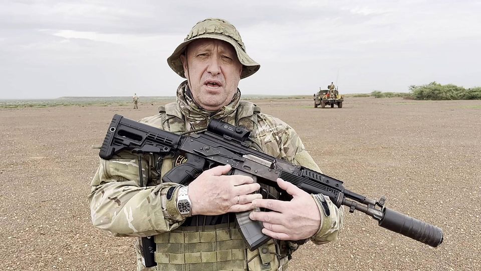 Jewgenij Prigoschin in Tarnkleidung und Maschinenpistole im Arm