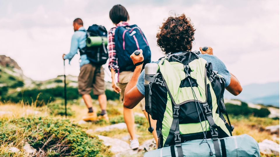 Geschenke für Wanderer und Outdoorfans: Drei Wanderer mit Gepäck auf einem Trailpfad