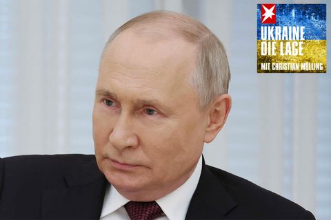 Wladimir Putin sitzt in Anzug und Krawatte da und lächelt leicht