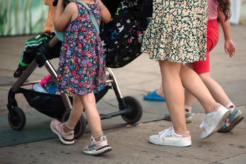 Einigung bei Kindergrundsicherung: Eine Frau schiebt einen Kinderwagen und geht begleitet von mehreren Kindern
