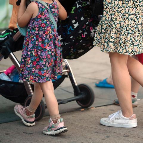 Einigung bei Kindergrundsicherung: Eine Frau schiebt einen Kinderwagen und geht begleitet von mehreren Kindern