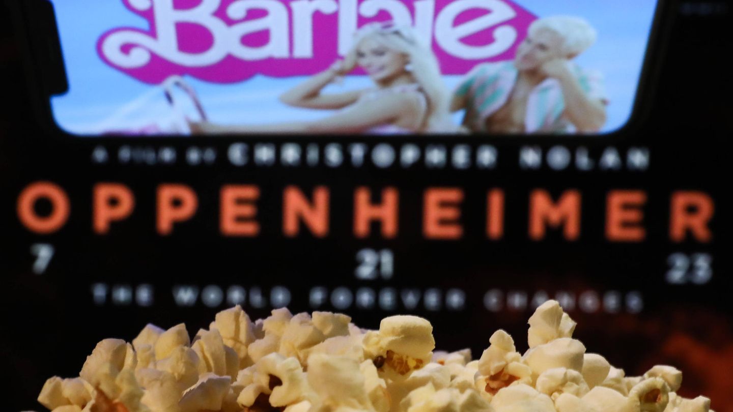 Eine Tüte Popcorn vor einer Kinoleinwand, auf der Barbie und Oppenheimer zu sehen sind