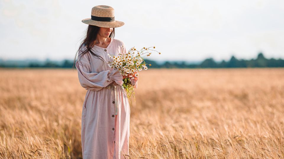 Eine Frau steht auf einem Kornfeld und trägt ein Oversize Kleid.