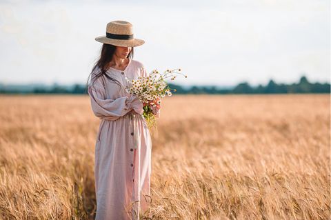 Eine Frau steht auf einem Kornfeld und trägt ein Oversize Kleid.