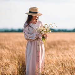 Eine Frau steht auf einem Kornfeld und trägt ein Oversize Kleid.