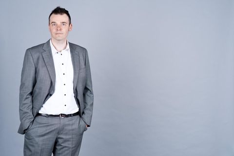 Ein Mann in Anzug vor grauen Wand