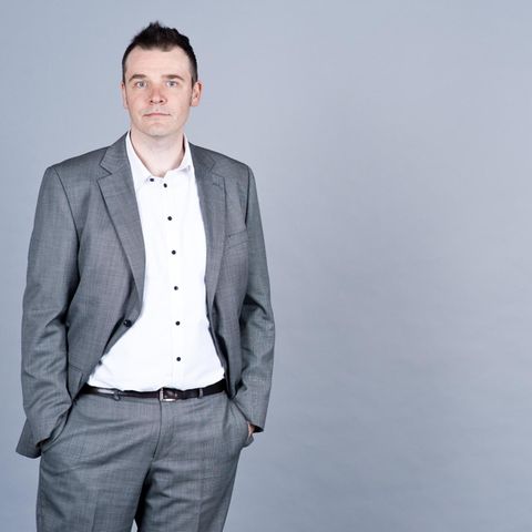 Ein Mann in Anzug vor grauen Wand