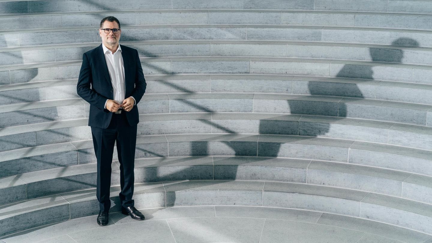 Wolgang Schmidt steht im Anzug vor Treppen