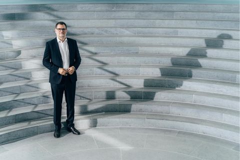 Wolgang Schmidt steht im Anzug vor Treppen