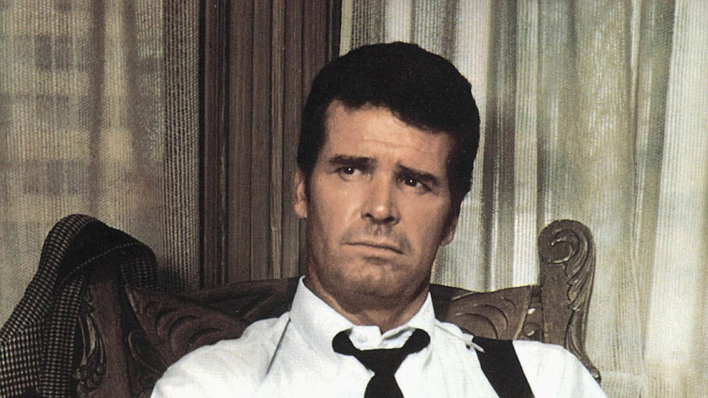 Philip Marlowe: Ein Mann mit loser Krawatte sitzt auf einem Stuhl und schaut ernst