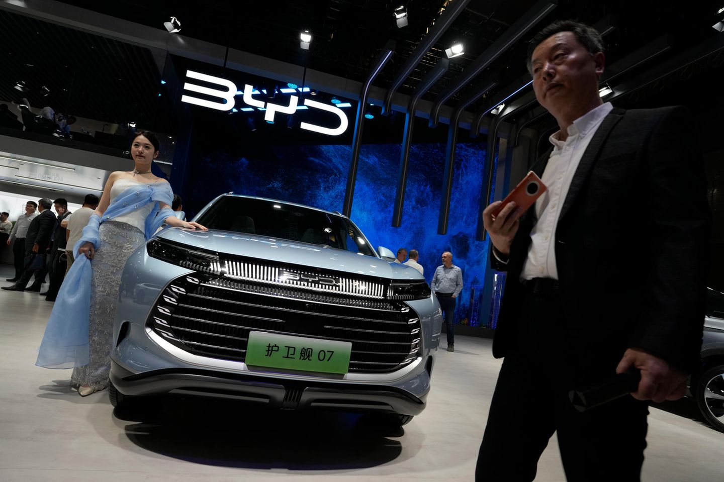 Ein Modell steht neben einem Auto von BYD während der Shanghai Auto Show im April 2023