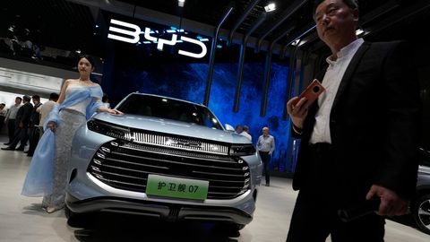 Ein Modell steht neben einem Auto von BYD während der Shanghai Auto Show im April 2023