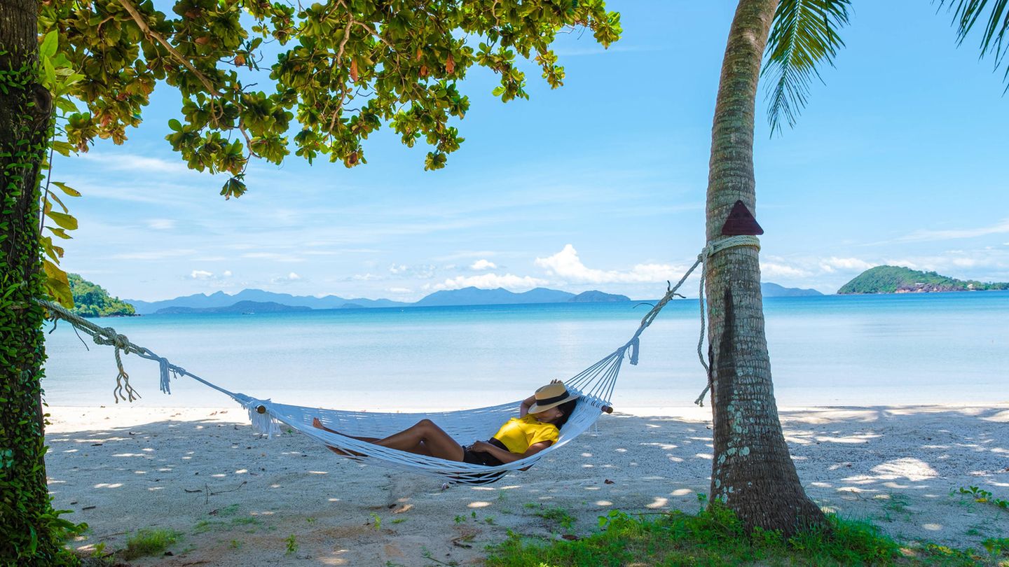 Urlaub: Frau liegt am Strand in einer Hängematte