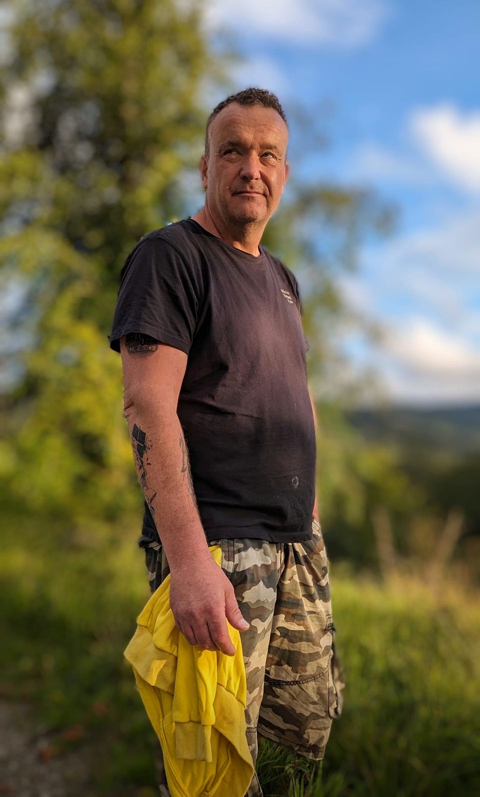 Ein Mann steht mit Tarnhose in der Natur