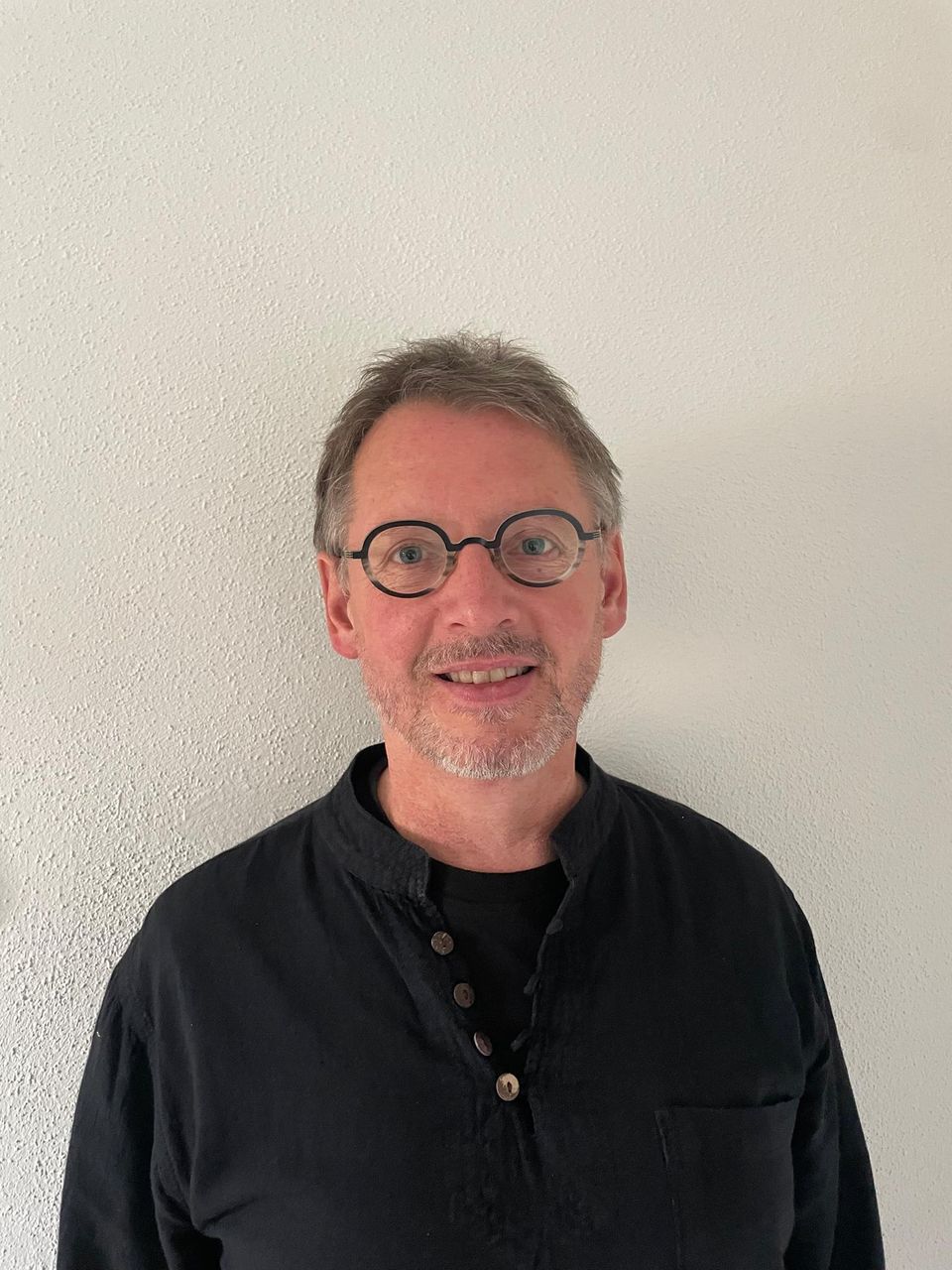 Ein Mann mit runder Brille und schwarzem Hemd