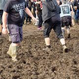 Fans laufen auf dem Wacken-Festival mit Gummistiefel durch den Schlamm