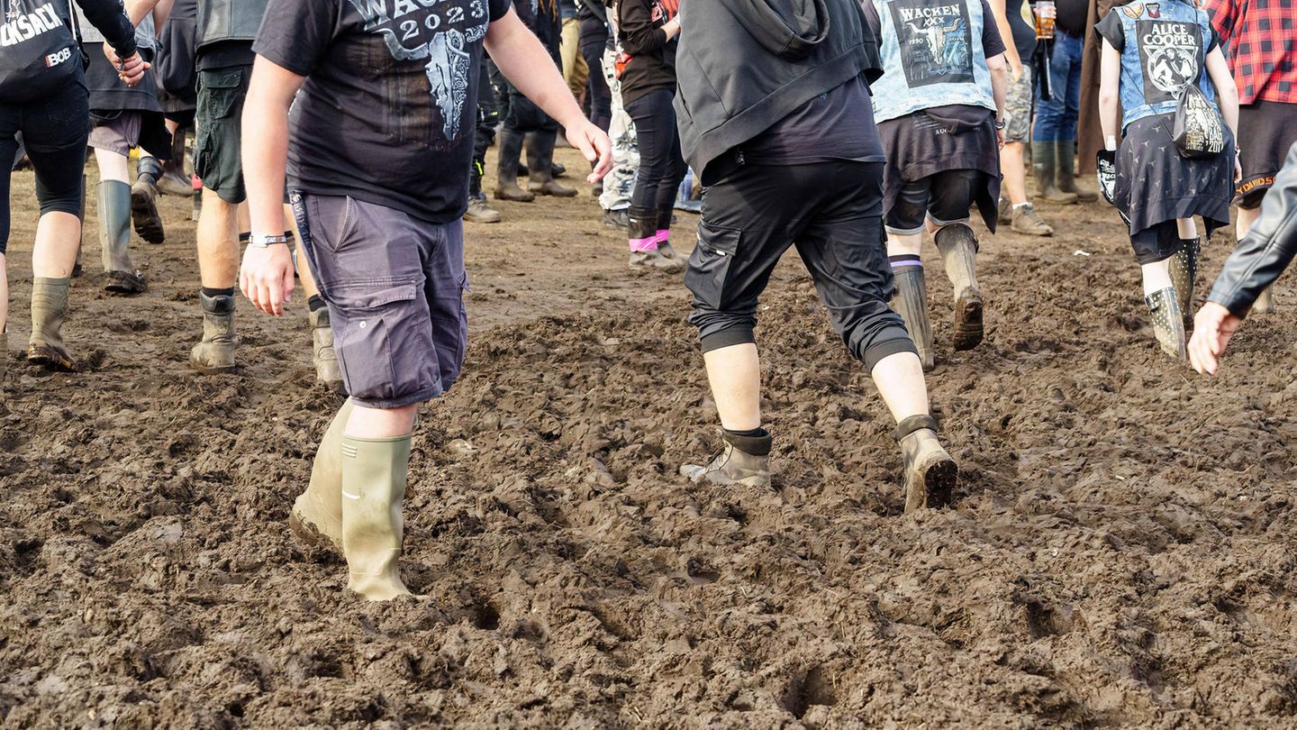 Fans laufen auf dem Wacken-Festival mit Gummistiefel durch den Schlamm